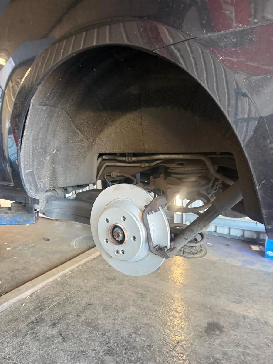 Brake disc and suspension exposed during brake work on a car at the Chertsey workshop