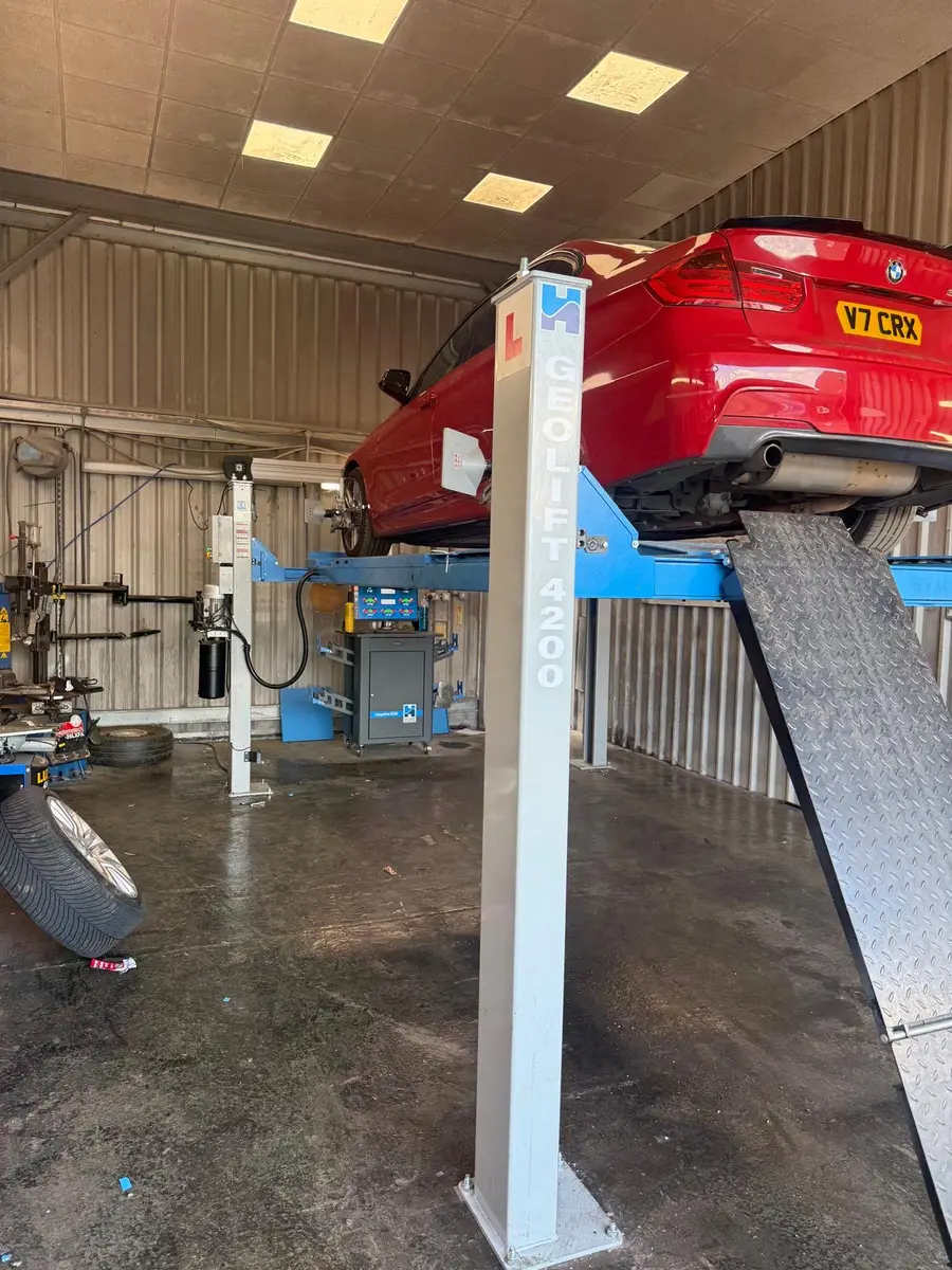 A car raised on the wheel alignment ramp inside the Chertsey workshop